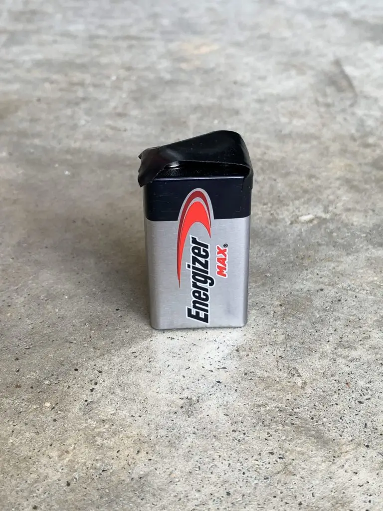 An energizer max aa battery standing upright on a concrete surface.