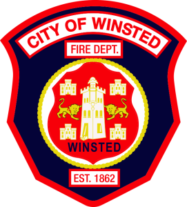 Badge-shaped logo for the City of Winsted Fire Department. Features a central seal with a tower, two lions, and buildings, surrounded by "Winsted" and "Est. 1862." The words "City of Winsted Fire Dept." are at the top.
